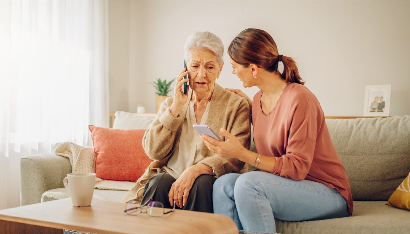 Seniorka i bliska osoba wspólnie analizujące wiadomość na telefonie